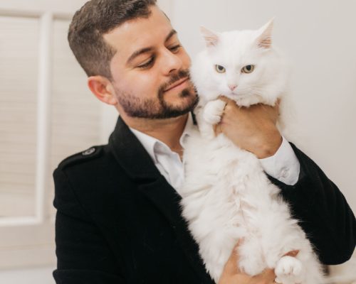 Dr. Charles Lima segurando um gato branco na clínica veterinária Império para Gatos em Pelotas.